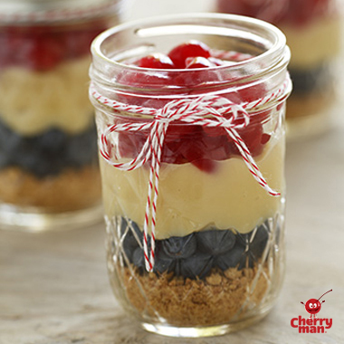 Cherry parfait with homemade pudding and blueberries served in mason jar. 